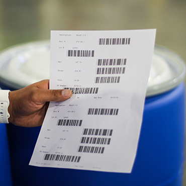 person holding sheet of paper with a barcode and information