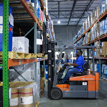 man in blue polo on a forklift pulling product from a shelf